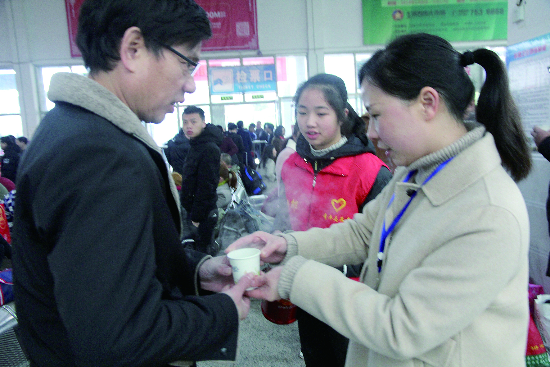 母女服務(wù)春運(yùn) 2月13日，記者在新邵分公司汽車站看到，該分公司安全科副科長李喜梅與其在新邵一中初中部1701班就讀女兒劉嘉怡在車站擔(dān)當(dāng)志愿者。李喜梅在候車室耐心為旅客釋疑解惑，劉嘉怡為旅客遞上一杯杯熱茶，有時(shí)母女也相互合作，其樂融融。 祖冠 攝影報(bào)道